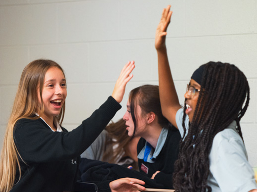 Two La Salle Institute students high-five in a lesson